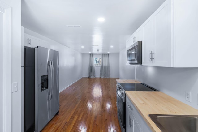 kitchen featuring butcher block countertops, dark hardwood / wood-style flooring, white cabinets, and stainless steel appliances