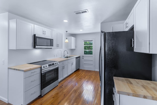 kitchen featuring white cabinetry, hanging light fixtures, wooden counters, and appliances with stainless steel finishes