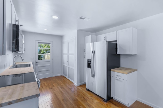 kitchen with butcher block counters, white cabinetry, sink, and appliances with stainless steel finishes