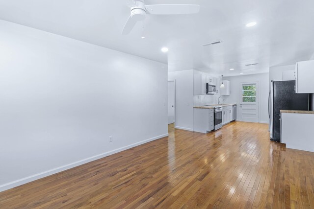 unfurnished living room featuring ceiling fan, sink, and light hardwood / wood-style flooring