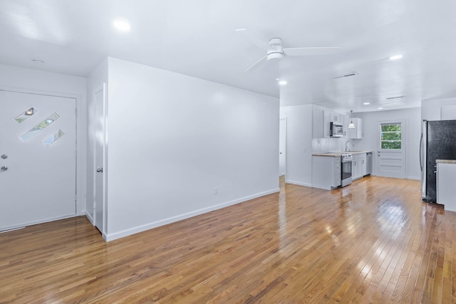 unfurnished living room featuring light hardwood / wood-style floors, ceiling fan, and sink