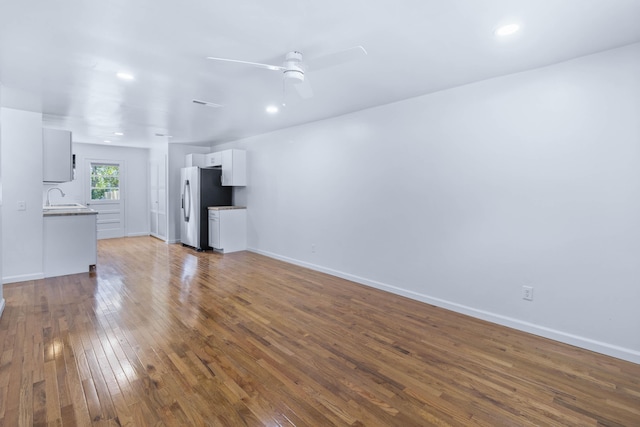 unfurnished living room with hardwood / wood-style flooring, ceiling fan, and sink