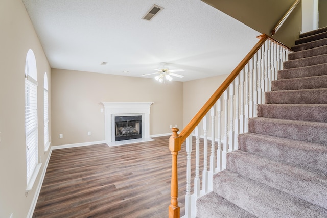 stairway with hardwood / wood-style flooring, ceiling fan, and a textured ceiling