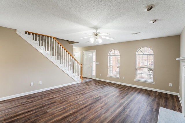 interior space featuring a fireplace, ceiling fan, dark hardwood / wood-style flooring, and a textured ceiling