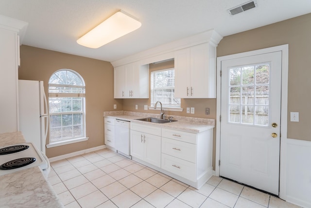 kitchen with white cabinets, plenty of natural light, white appliances, and sink