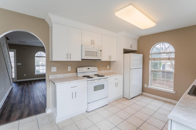 kitchen featuring white cabinetry, light tile patterned floors, and white appliances