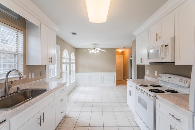 kitchen featuring white appliances, ceiling fan, sink, light tile patterned floors, and white cabinetry