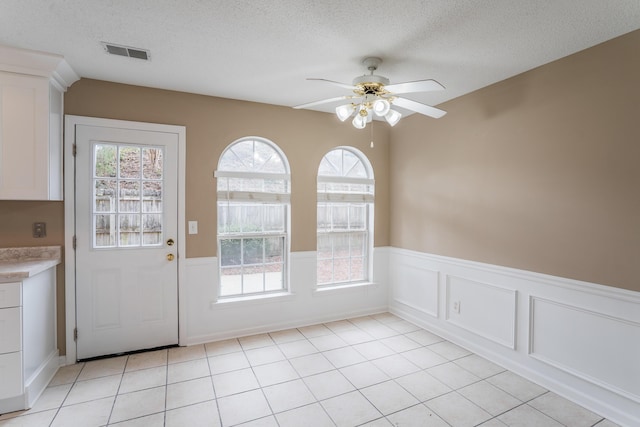 doorway to outside featuring light tile patterned floors, a textured ceiling, ceiling fan, and a healthy amount of sunlight