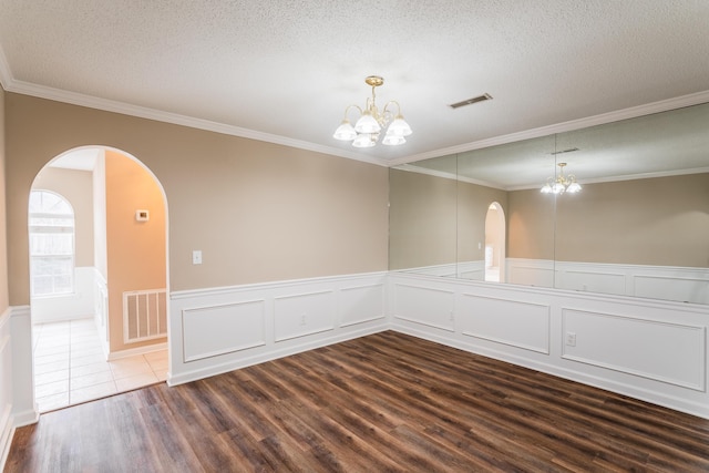 empty room with a chandelier, a textured ceiling, hardwood / wood-style flooring, and ornamental molding