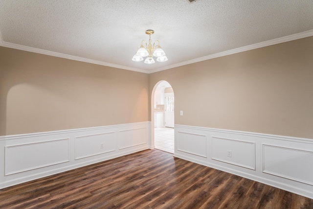 empty room featuring a textured ceiling, dark wood-type flooring, an inviting chandelier, and ornamental molding