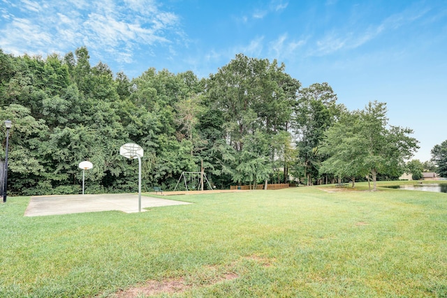 view of yard with basketball hoop, a water view, and a playground