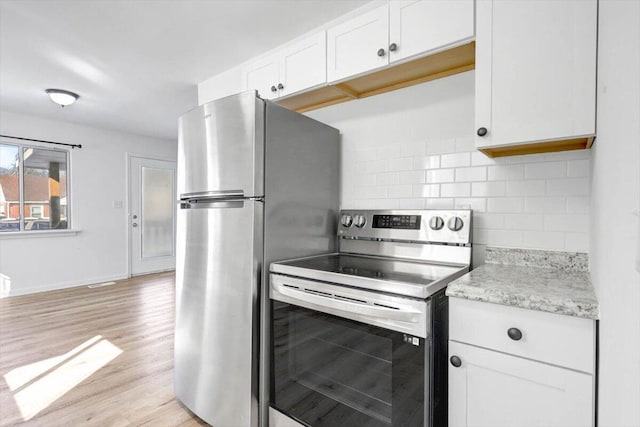 kitchen with white cabinets, light stone countertops, light wood-type flooring, tasteful backsplash, and stainless steel appliances