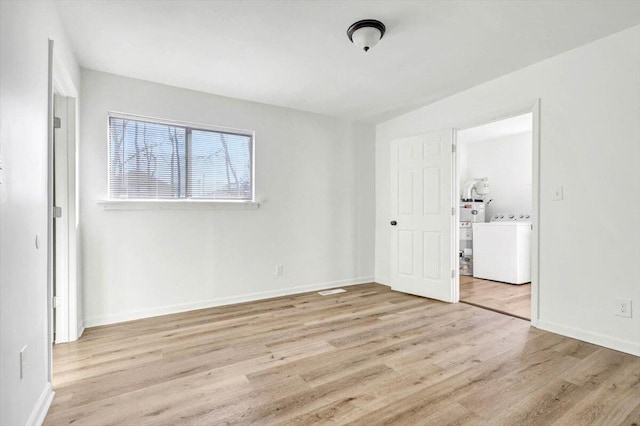 unfurnished bedroom with light hardwood / wood-style floors and washer / dryer