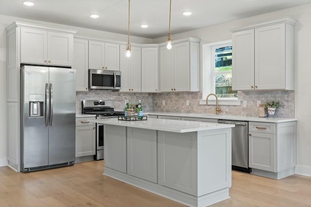 kitchen featuring a center island, white cabinets, hanging light fixtures, sink, and appliances with stainless steel finishes