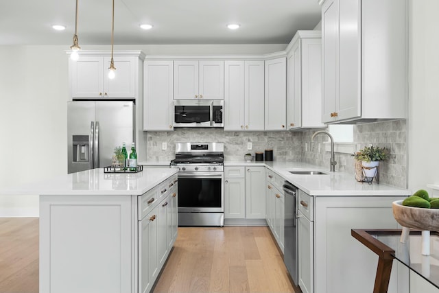 kitchen with hanging light fixtures, white cabinetry, sink, and stainless steel appliances