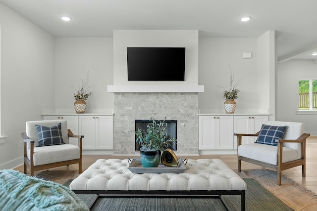 living room with light wood-type flooring and a tiled fireplace