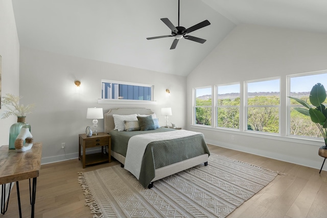 bedroom featuring ceiling fan, light hardwood / wood-style flooring, and high vaulted ceiling