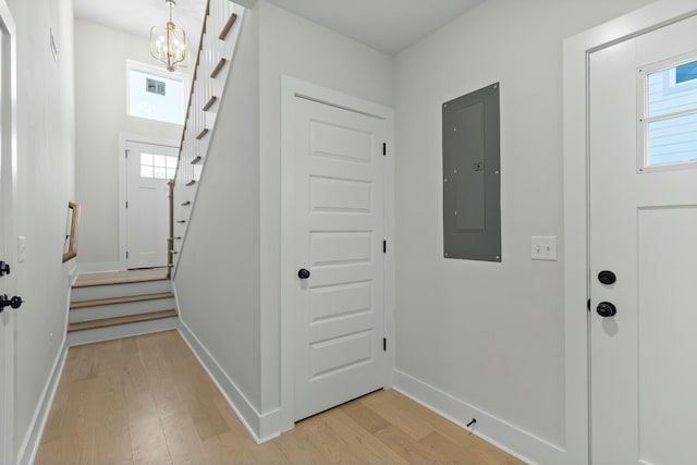 entrance foyer with a healthy amount of sunlight, light wood-type flooring, electric panel, and a chandelier