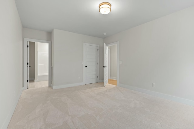 unfurnished bedroom featuring connected bathroom, light carpet, and a closet