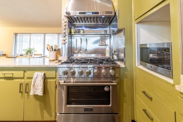 kitchen featuring light stone counters, wall chimney exhaust hood, and appliances with stainless steel finishes