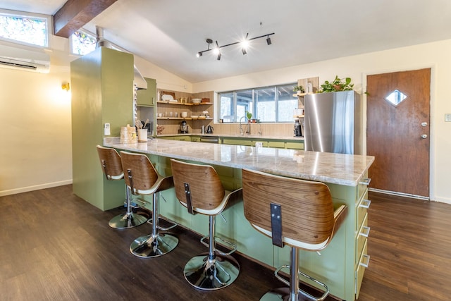 kitchen featuring stainless steel fridge, vaulted ceiling with beams, a wall unit AC, dark hardwood / wood-style flooring, and kitchen peninsula