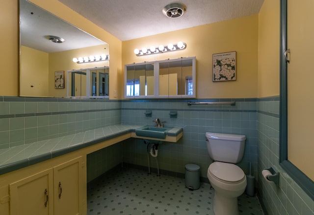 bathroom with sink, tile walls, and toilet