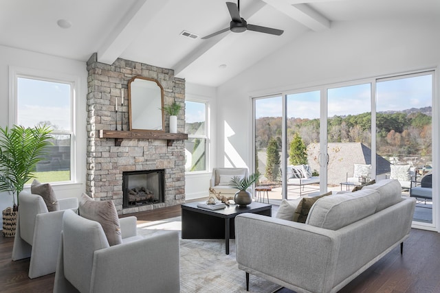 living room featuring vaulted ceiling with beams, ceiling fan, dark hardwood / wood-style floors, and a stone fireplace