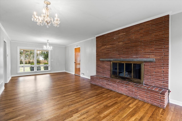 unfurnished living room with a brick fireplace, a notable chandelier, hardwood / wood-style flooring, and ornamental molding