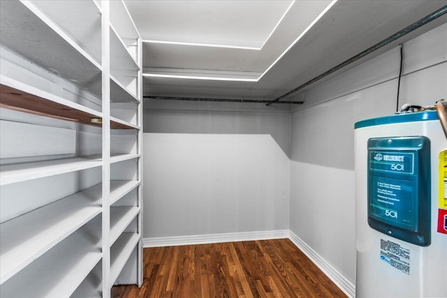 spacious closet featuring water heater and dark wood-type flooring