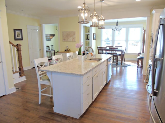 kitchen with pendant lighting, sink, a kitchen island with sink, white cabinetry, and light stone countertops