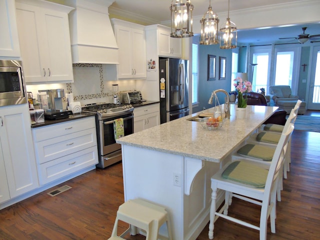 kitchen featuring sink, a breakfast bar, premium range hood, appliances with stainless steel finishes, and an island with sink