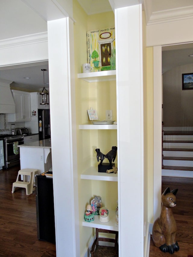 interior space with premium range hood, built in shelves, crown molding, stainless steel electric range, and black refrigerator