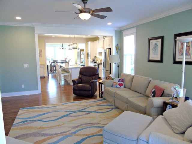 living room with crown molding, ceiling fan with notable chandelier, and light hardwood / wood-style floors