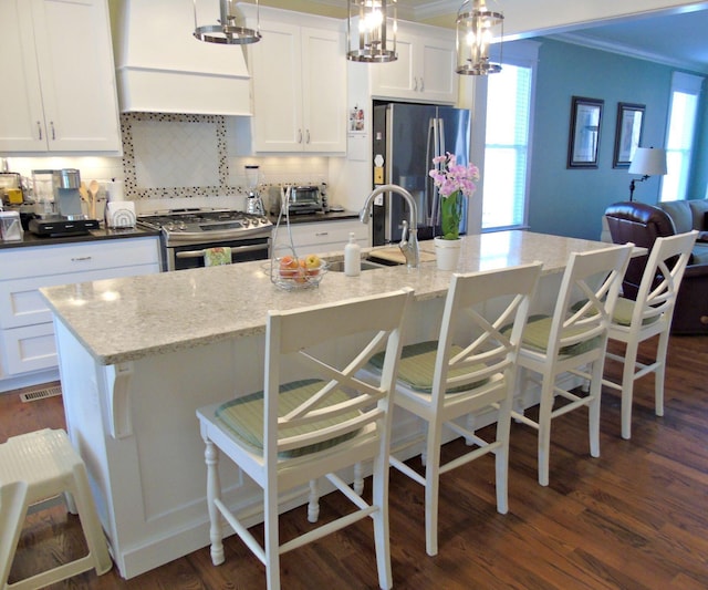 kitchen with pendant lighting, stainless steel appliances, a kitchen breakfast bar, and a center island with sink