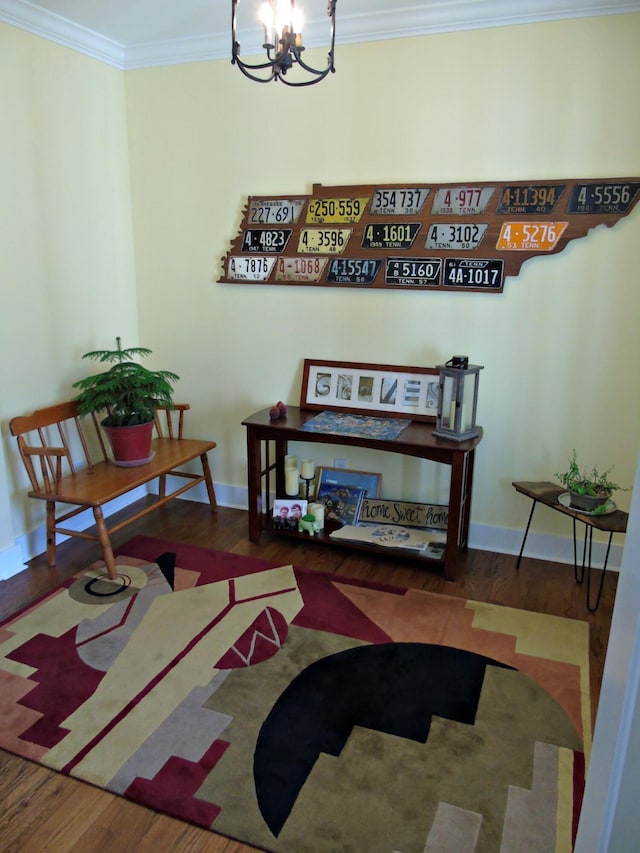 living area with a notable chandelier, wood-type flooring, and ornamental molding