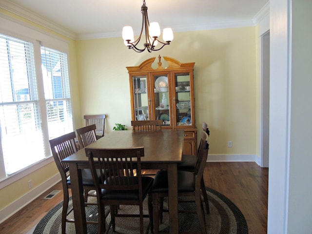 dining space featuring crown molding, dark wood-type flooring, and a notable chandelier