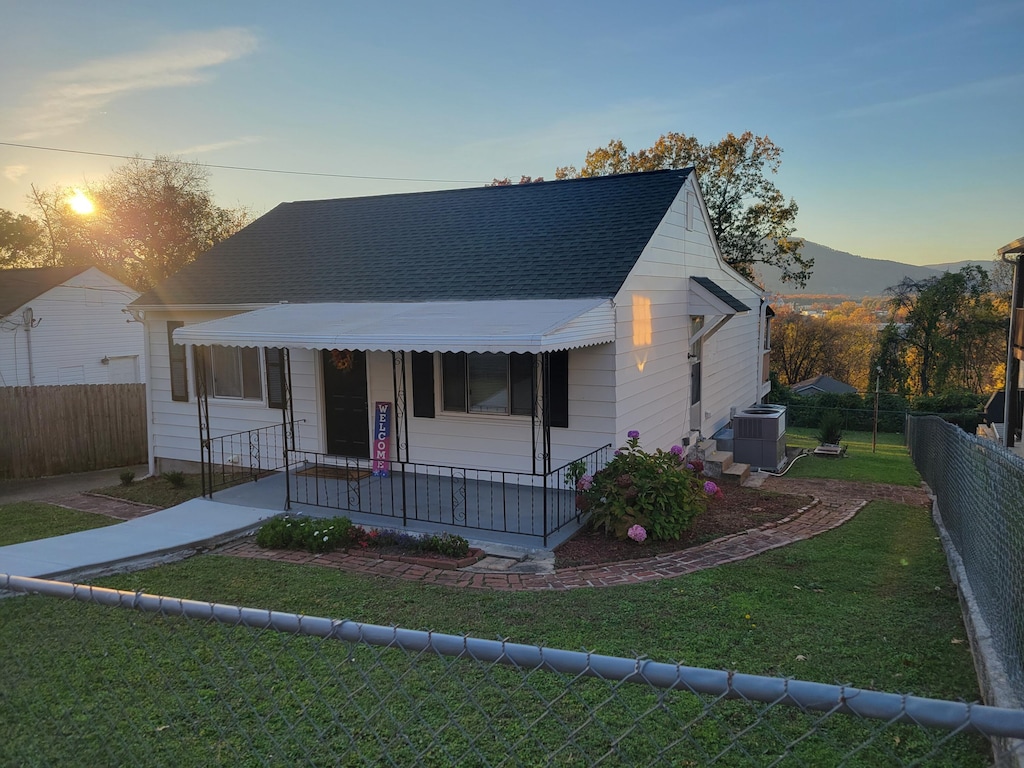 bungalow-style home featuring a mountain view, cooling unit, a lawn, and covered porch