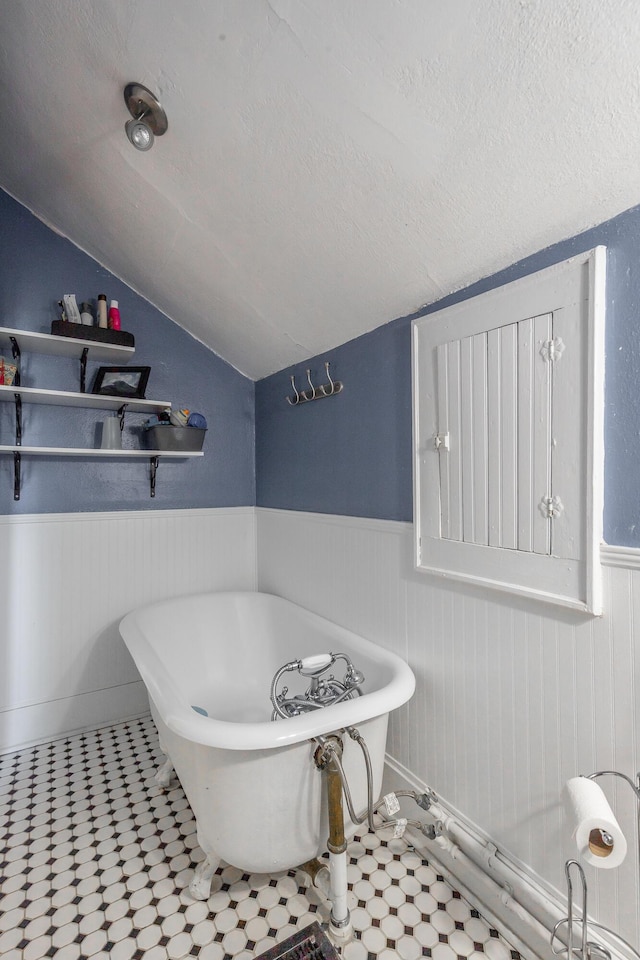 bathroom with lofted ceiling, a textured ceiling, and a bath