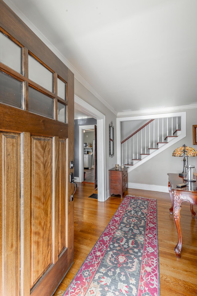 entryway with wood-type flooring and crown molding