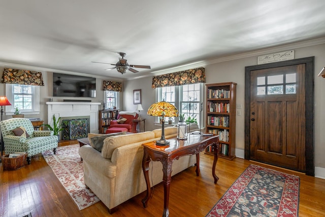 living room with ceiling fan, ornamental molding, a fireplace, and hardwood / wood-style floors