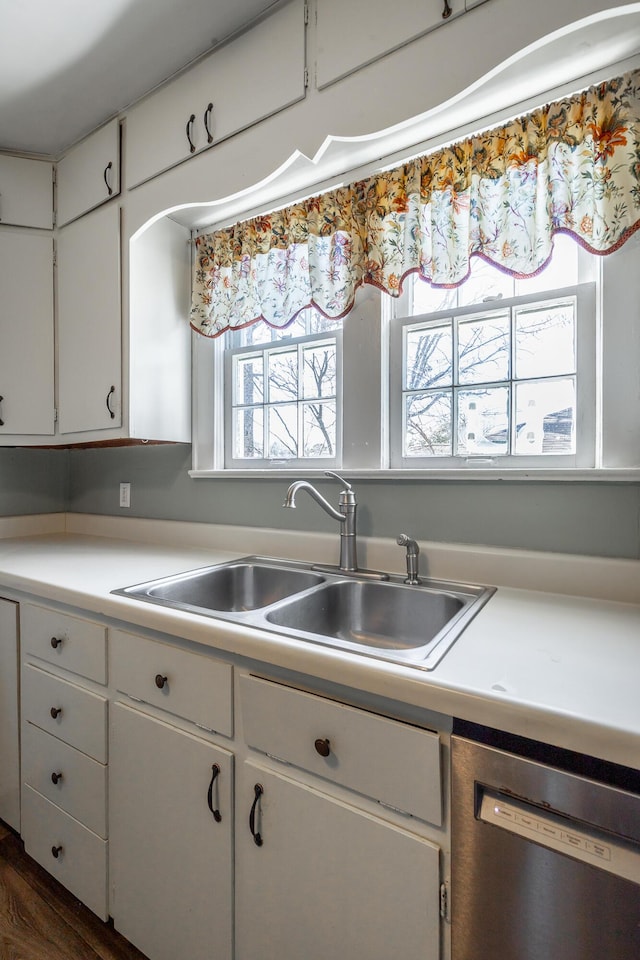 kitchen with dark wood-type flooring, sink, white cabinetry, and stainless steel dishwasher