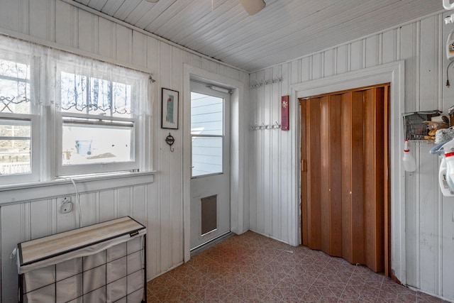 doorway to outside with wood walls