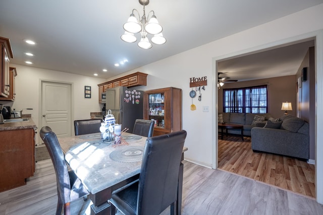 dining room featuring light hardwood / wood-style flooring and ceiling fan with notable chandelier