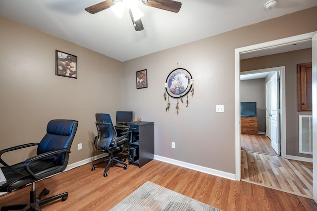 home office with light wood-type flooring and ceiling fan