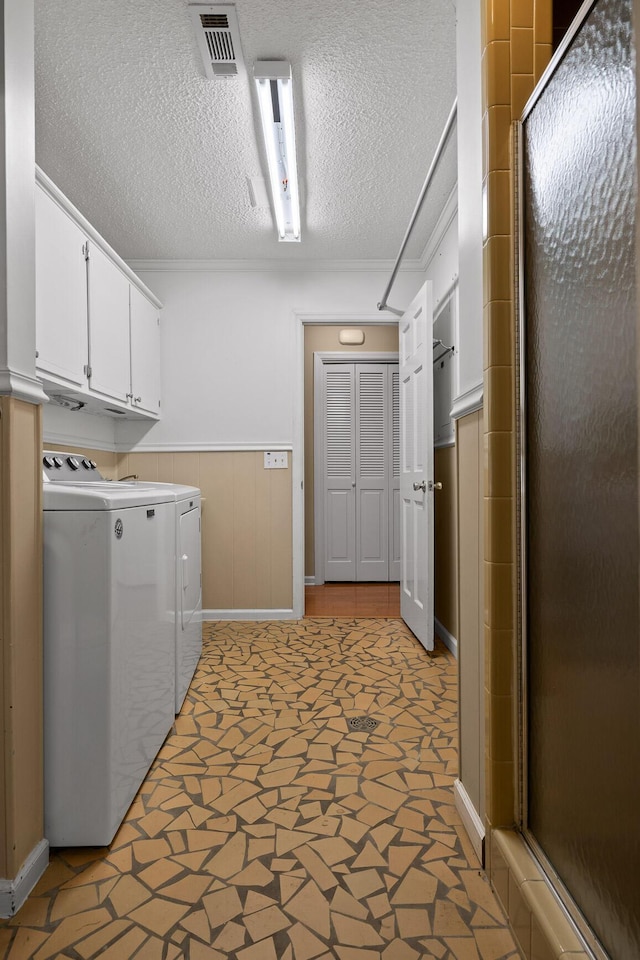 laundry area featuring separate washer and dryer, cabinets, and a textured ceiling