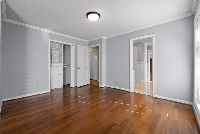 unfurnished bedroom with dark wood-type flooring, ornamental molding, a closet, and a textured ceiling