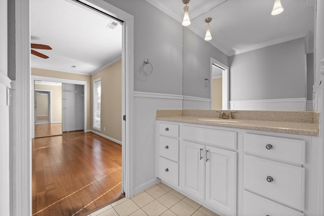 bathroom with hardwood / wood-style flooring, ceiling fan, ornamental molding, and vanity