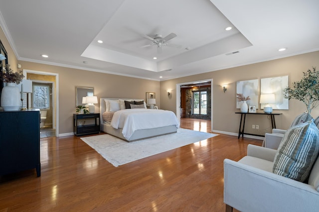 bedroom featuring hardwood / wood-style flooring, crown molding, ceiling fan, and a tray ceiling