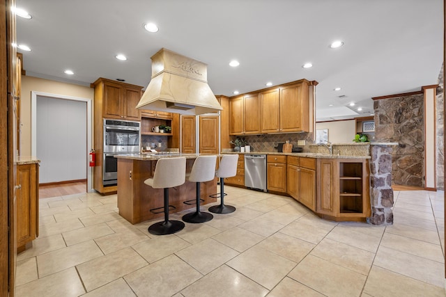 kitchen with a breakfast bar, tasteful backsplash, custom range hood, kitchen peninsula, and stainless steel double oven