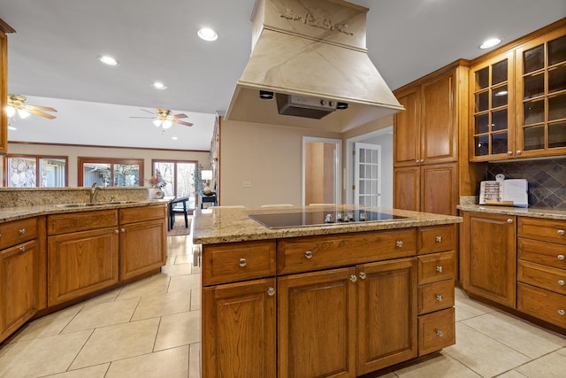 kitchen with light tile patterned flooring, sink, light stone countertops, custom range hood, and black electric cooktop